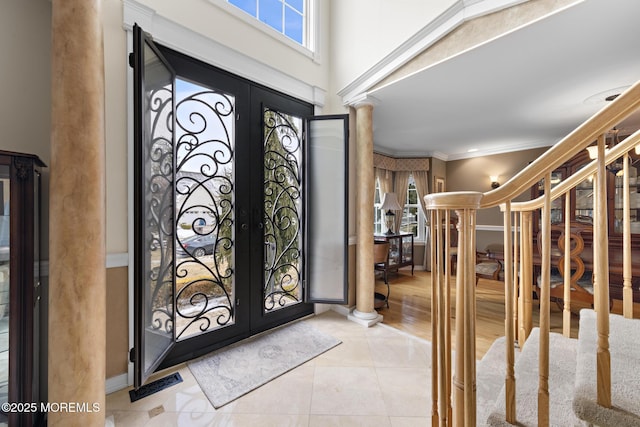 entryway with decorative columns, light tile patterned flooring, crown molding, and french doors