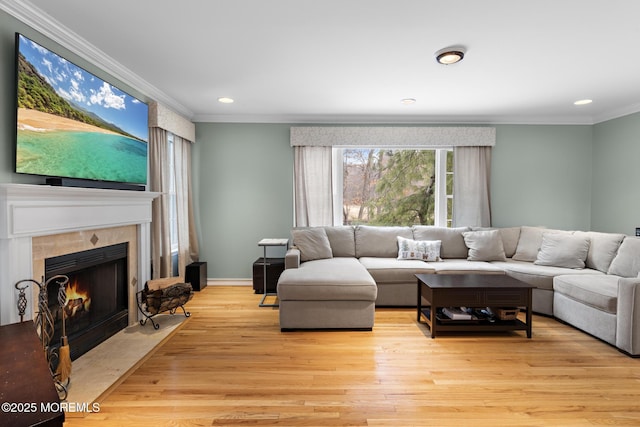 living area with light wood-style flooring, recessed lighting, baseboards, a tiled fireplace, and crown molding