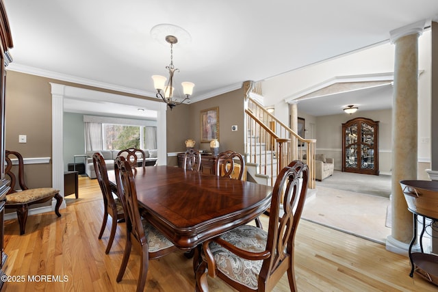 dining room with ornamental molding, light wood-type flooring, decorative columns, and an inviting chandelier