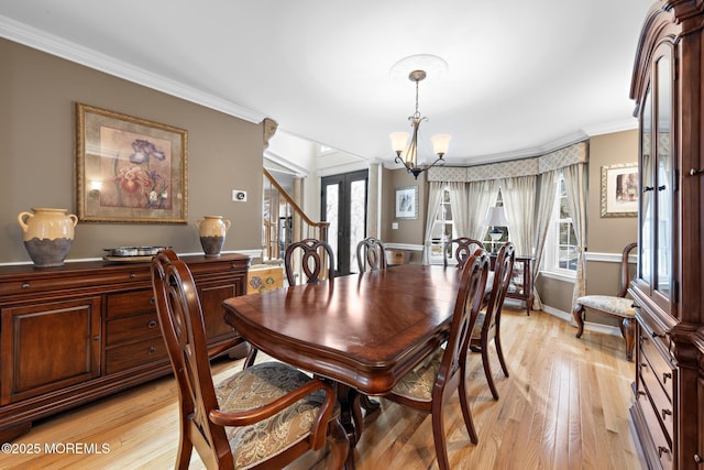 dining room featuring crown molding, stairway, an inviting chandelier, light wood-type flooring, and baseboards