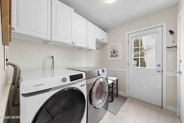 laundry room featuring washing machine and dryer, cabinet space, and baseboards