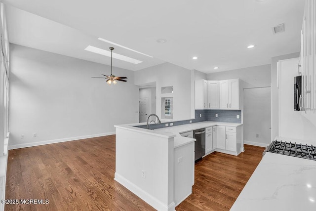 kitchen with white cabinets, light stone counters, a skylight, and kitchen peninsula