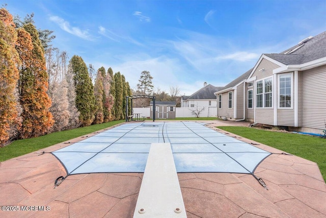 view of swimming pool featuring a shed, a patio, and a yard