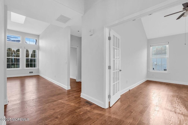 empty room with ceiling fan, plenty of natural light, vaulted ceiling, and dark hardwood / wood-style floors