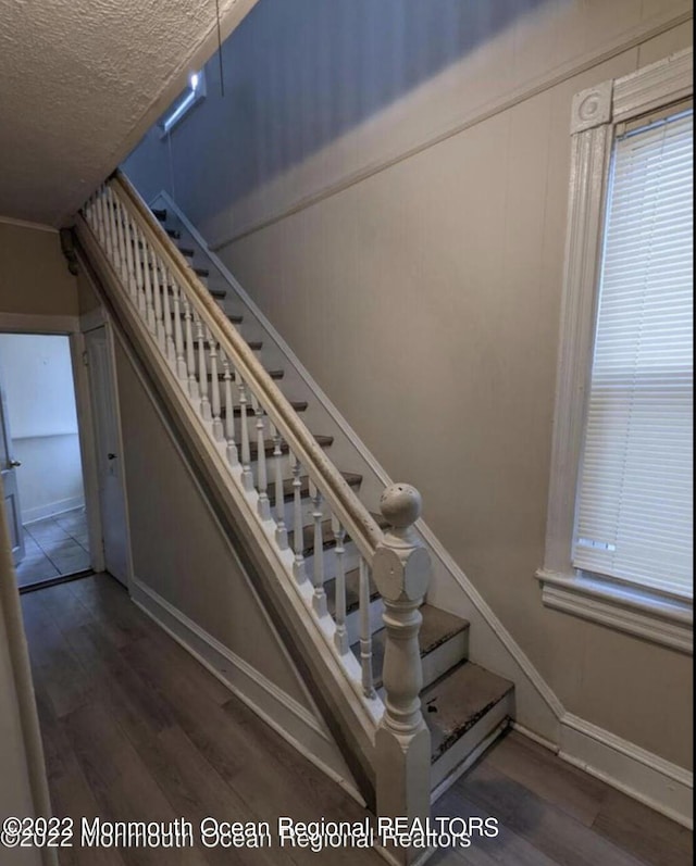 staircase featuring a textured ceiling and hardwood / wood-style flooring