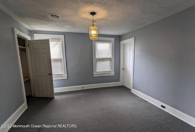 empty room with dark colored carpet and a textured ceiling