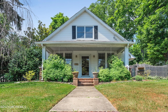 bungalow-style home featuring a porch, a front yard, and fence