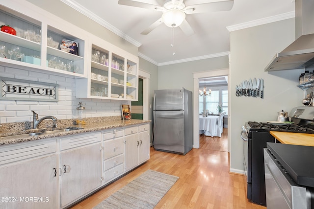 kitchen featuring stainless steel appliances, a sink, white cabinets, wall chimney range hood, and glass insert cabinets