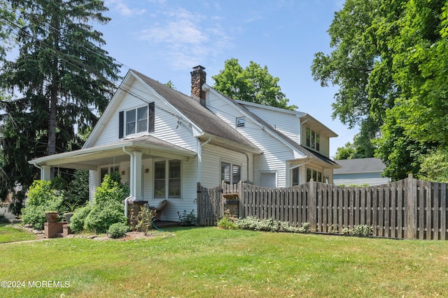 view of front of home featuring a front lawn, a chimney, and fence