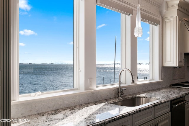 kitchen featuring sink, a water view, pendant lighting, dark stone counters, and white cabinets