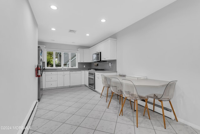 kitchen featuring light tile patterned flooring, appliances with stainless steel finishes, white cabinetry, and a baseboard heating unit