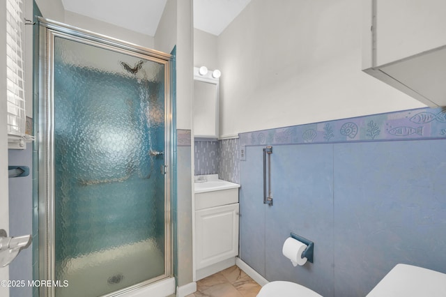 bathroom featuring a stall shower, marble finish floor, wainscoting, and toilet