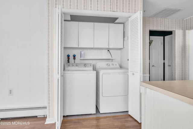 washroom featuring light wood-style floors, baseboard heating, cabinet space, washing machine and clothes dryer, and wallpapered walls