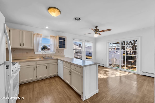 kitchen with light countertops, white appliances, a peninsula, and a sink