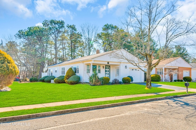 view of front facade with a garage, a chimney, aphalt driveway, and a front yard