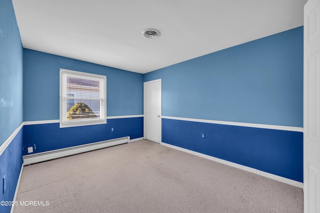 unfurnished room with baseboard heating, carpet, visible vents, and baseboards