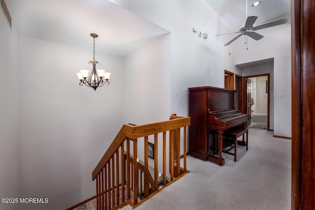 corridor with visible vents, baseboards, light colored carpet, an upstairs landing, and a notable chandelier