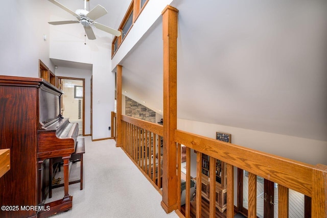 hall featuring lofted ceiling, baseboards, and light colored carpet