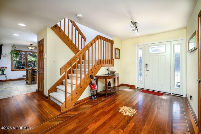 foyer with stairway, dark wood finished floors, and baseboards