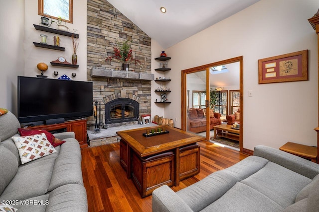 living area featuring high vaulted ceiling, dark wood-style flooring, and a stone fireplace