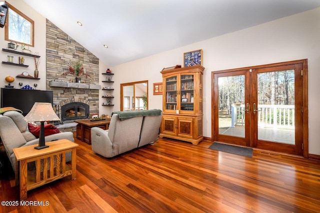 living area featuring high vaulted ceiling, french doors, wood finished floors, and a stone fireplace