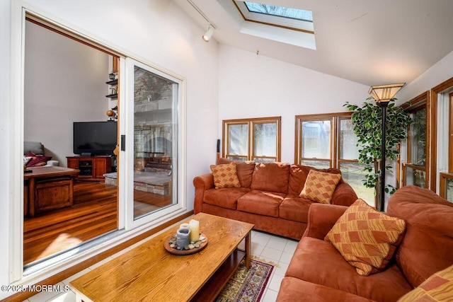 living area featuring lofted ceiling with skylight, light tile patterned floors, and rail lighting