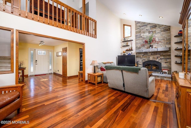 living area with stairs, a stone fireplace, wood finished floors, and a healthy amount of sunlight