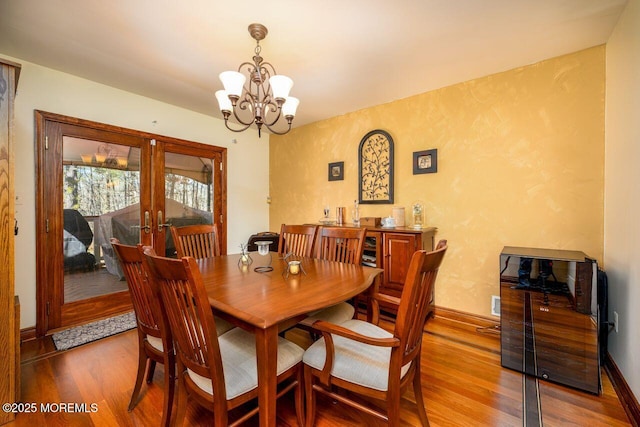 dining area featuring a chandelier, french doors, baseboards, and wood finished floors