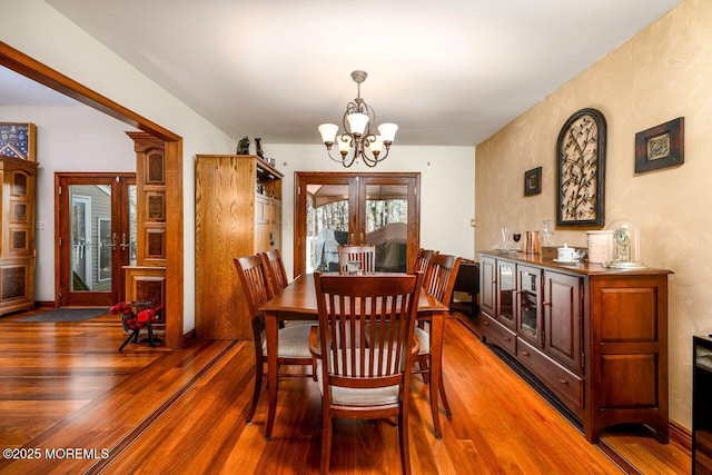 dining space with a chandelier, french doors, and wood finished floors