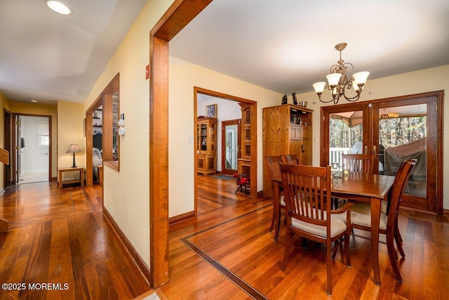 dining area featuring a notable chandelier, baseboards, and wood finished floors