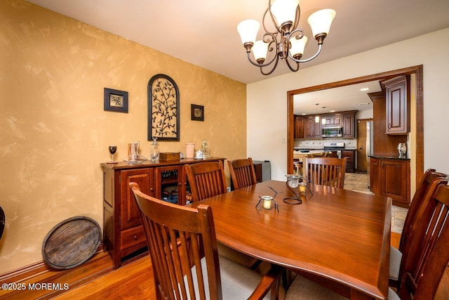 dining space featuring light wood-type flooring and an inviting chandelier