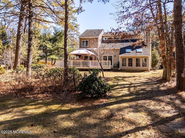 back of property featuring a chimney, a yard, a deck, and a gazebo