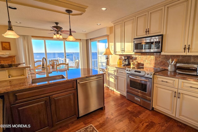 kitchen featuring appliances with stainless steel finishes, a sink, cream cabinetry, and tasteful backsplash