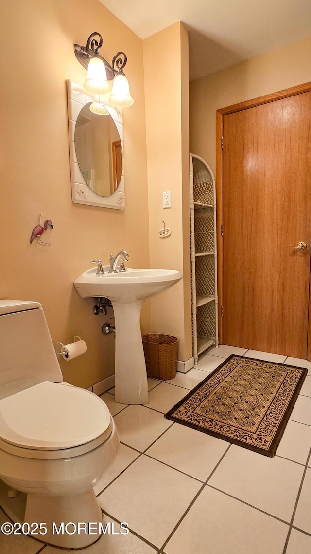 bathroom featuring toilet, tile patterned flooring, and a sink