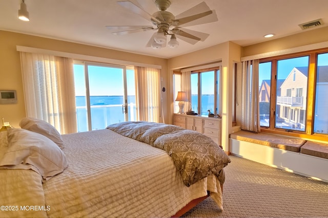 carpeted bedroom featuring a water view, access to exterior, ceiling fan, and visible vents