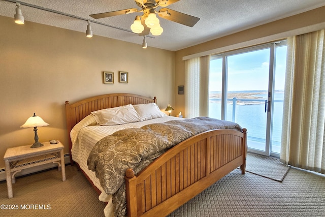 bedroom featuring a ceiling fan, a water view, access to outside, a textured ceiling, and carpet flooring