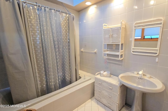 bathroom with tiled shower / bath combo, tile patterned flooring, tasteful backsplash, and tile walls