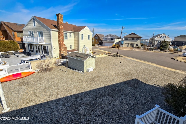 view of yard featuring a balcony, a residential view, and fence