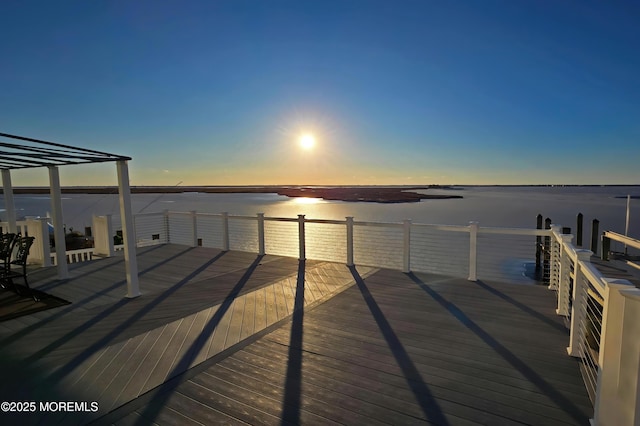 deck at dusk featuring a water view