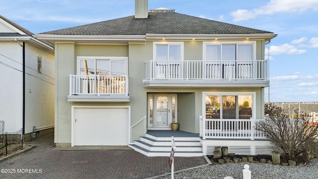 view of front of home featuring a balcony, an attached garage, decorative driveway, and stucco siding