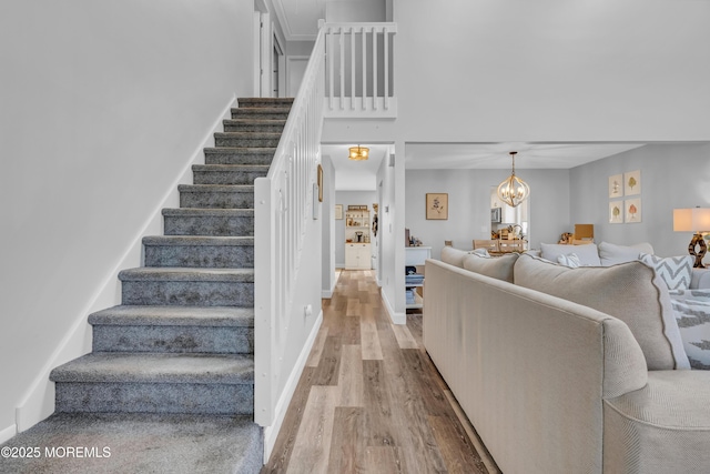 stairs with hardwood / wood-style floors, a high ceiling, and a notable chandelier