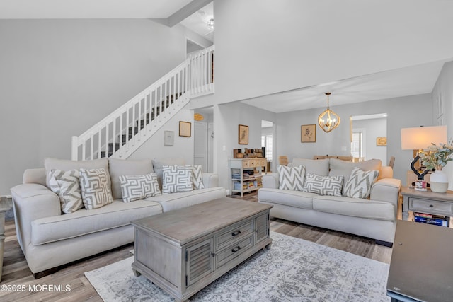 living room featuring hardwood / wood-style flooring, high vaulted ceiling, an inviting chandelier, and beamed ceiling