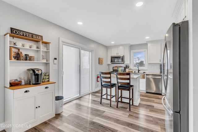 kitchen with a breakfast bar, white cabinetry, a kitchen island, butcher block countertops, and stainless steel appliances