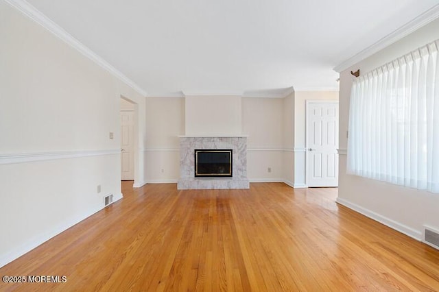 unfurnished living room with light wood-type flooring, a fireplace, and ornamental molding