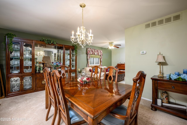 carpeted dining room with ceiling fan with notable chandelier