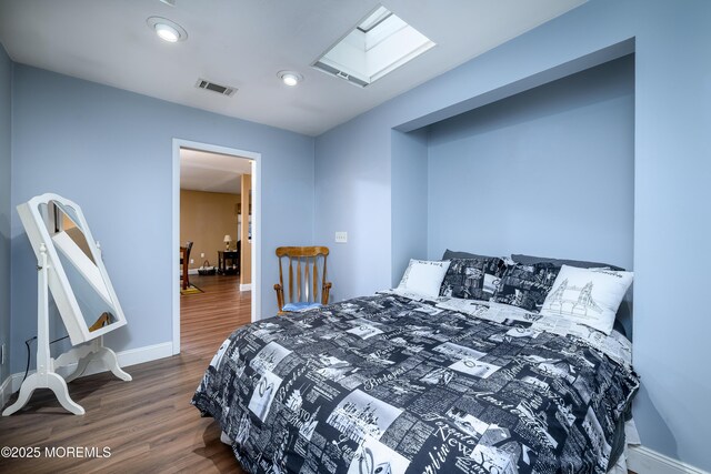 bedroom featuring a skylight and dark hardwood / wood-style floors