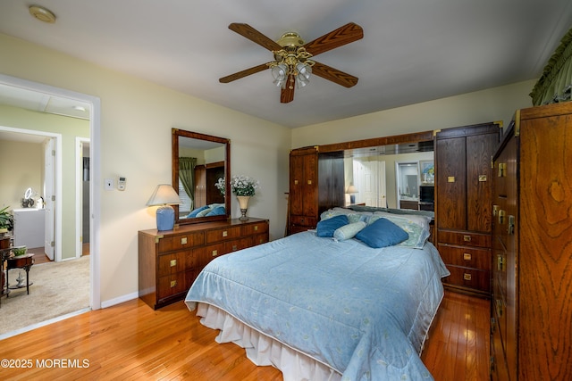 bedroom with light hardwood / wood-style flooring, ceiling fan, and a barn door