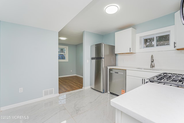 kitchen featuring sink, appliances with stainless steel finishes, white cabinets, and tasteful backsplash