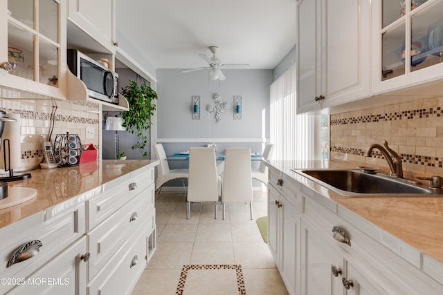 kitchen with white cabinets, ceiling fan, decorative backsplash, light tile patterned floors, and sink