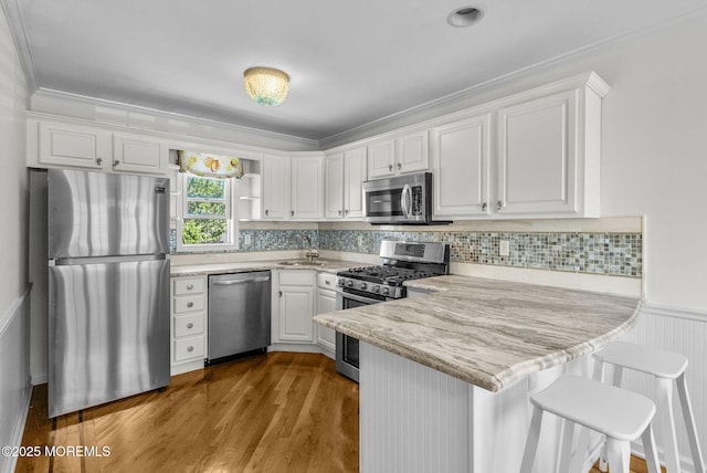 200 2nd Ave Unit 14, Belmar, NJ 07719 - kitchen featuring appliances with stainless steel finishes, a peninsula, white cabinetry, a sink, and crown molding